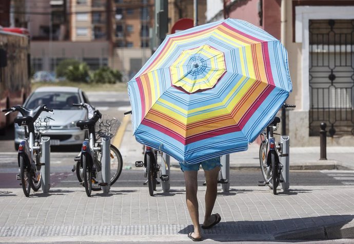 Archivo - Un hombre con una sombrilla cerca de la Playa de la Malvarrosa, a 12 de agosto de 2022, en Valencia, Comunidad Valenciana (España). Una DANA establecida en la Península Ibérica está provocando aumento de temperaturas en la parte este del país.
