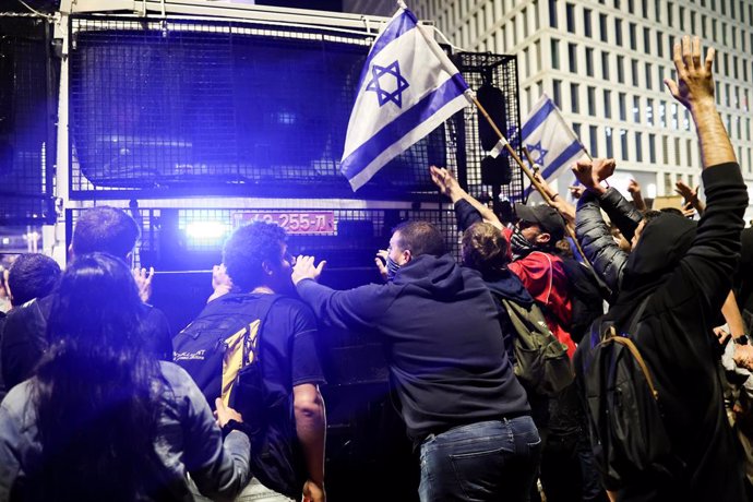 27 March 2023, Israel, Tel Aviv: Protesters block a police vehicle from dispersing a protest against Prime Minister Benjamin Netanyahu's planned overhaul of the legal system. After weeks of mass protests in Israel, Prime Minister Benjamin Netanyahu has 