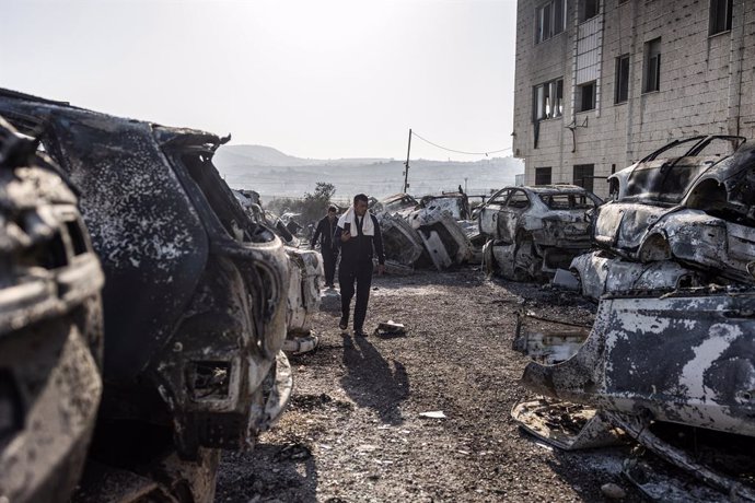 Archivo - Varias personas inspeccionan los vehículos quemados en la ciudad cisjordana de Huwara después de que los colonos incendiaran casas y coches.