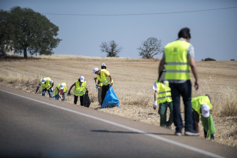 Voluntarios del proyecto Libera recogiendo basuraleza de una cuneta.