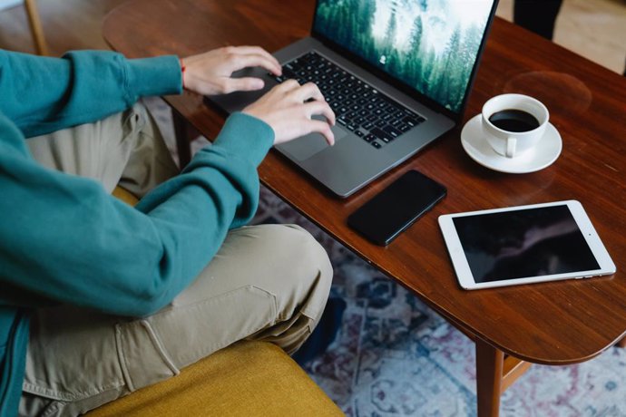 Archivo - Un hombre utilizando un ordenador, un móvil y una tableta