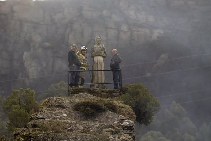 Dos hombres y un guarda forestal observan el monte quemado por un incendio forestal, a 30 de marzo de 2023, en Baleira, Lugo, Galicia.