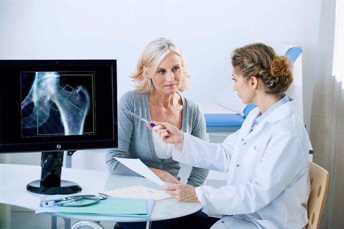 Doctora le muestra una radiografía a una paciente. 