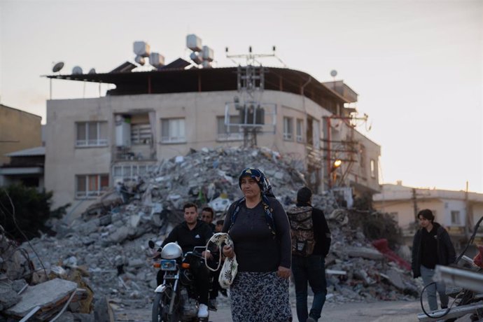Archivo - Varias personas dejan atrás los escombros de los edificios derribados por el terremoto en Iskenderun, Turquía
