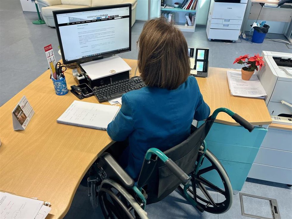 Archivo - Una empleada en silla de ruedas en su puesto de trabajo.