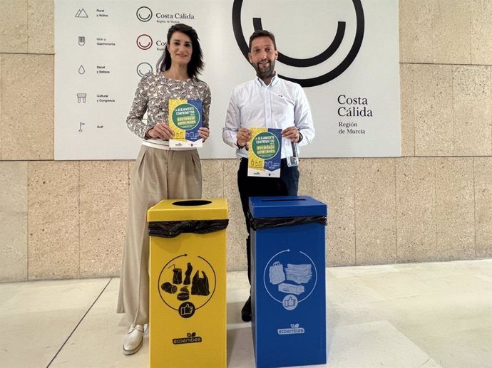 El director del Itrem, Juan Francisco Martínez, y Aída Fernando, de Ecoembes en la Región de Murcia, muestran las papeleras amarillas y azules que se instalarán en alojamientos turísticos.