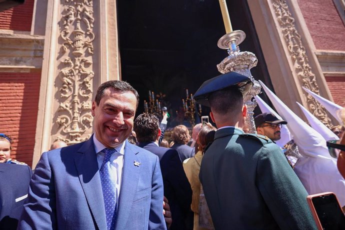 El presidente de la Junta de Andalucía, Juanma Moreno, espera la salida del paso de la Borriquita en la puerta de la Iglesia Colegial del Divino Salvador