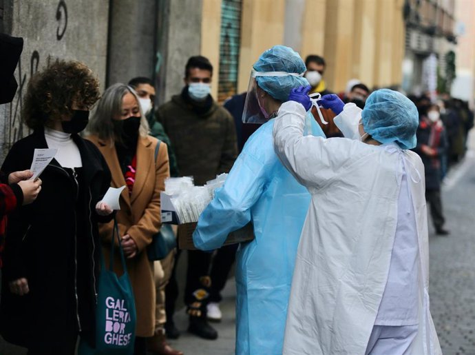 Archivo - Una sanitaria pone el EPI a otra sanitaria para recoges test de COVID-19 de las personas que hacen cola en el Centro de Salud Universidad, a 21 de diciembre de 2021, en Madrid, (España).