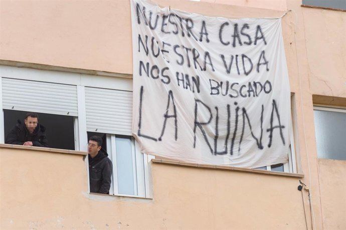 Archivo - Dos personas se asoman por la ventana durante el desalojo forzoso de las familias que viven en los apartamentos Don Pepe.