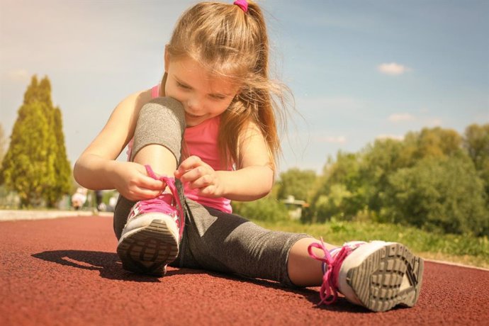 Archivo - Niña atándose los cordones de los zapatos.