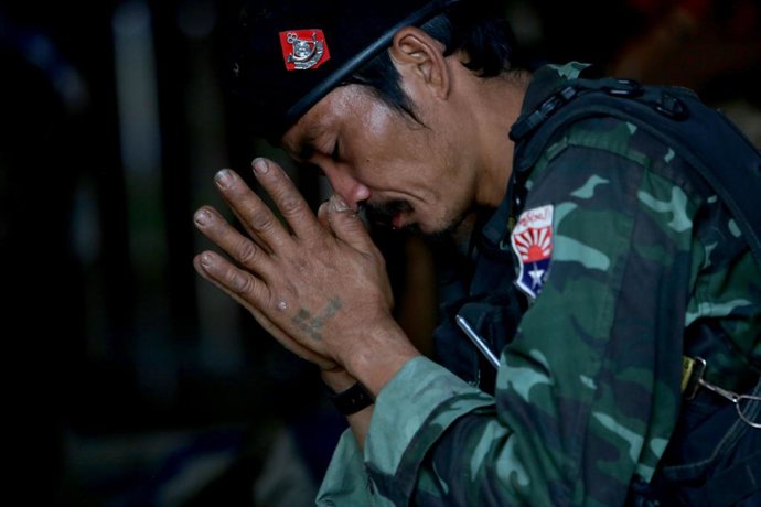 Archivo - February 20, 2022, Karen Sate, Burma Myanmar: A member of the young soldiers unit kneels and prays before the soldier. The dead KNLA fighters entire unit was called off the frontlines to attend the buddhist funeral ceremony. The KNLA have bee