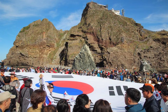 Archivo - Varias personas sostienen una bandera de Corea del Sur en las islas Dokdo, en disputa con Japón.