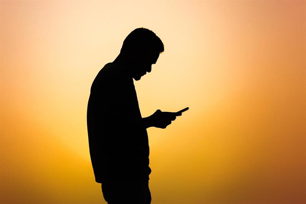 Archivo - Un hombre mira su teléfono