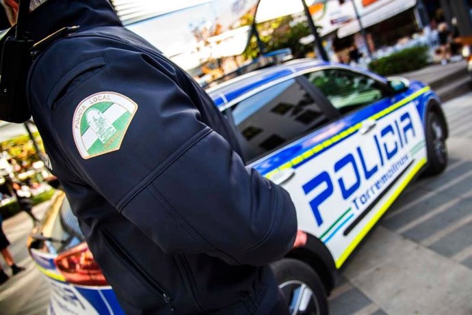 Agente de la Policía Local de Torremolinos, junto a un vehículo oficial