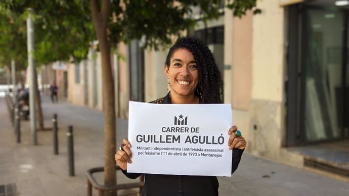 La candidata de la CUP a la Alcaldía de Barcelona, Basha Changue, con un cartel de la propuesta de calle con el nombre de Guillem Agulló.