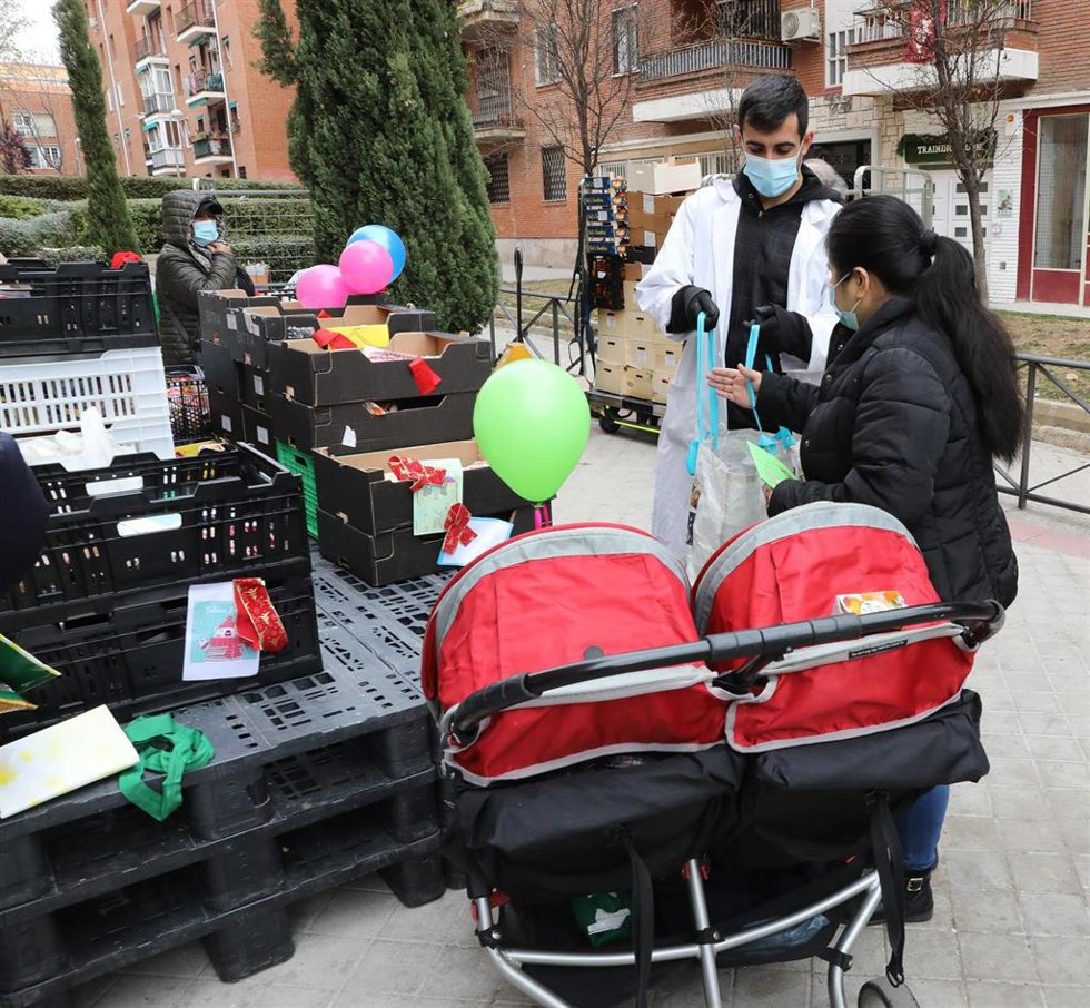 Archivo - Una mujer con un carrito doble recibe una cesta navideña entregada por la Fundación Madrina.