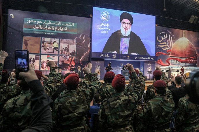 Archivo - 29 April 2022, Lebanon, Beirut: Pro-Iranian Hezbollah militants raise their fists to salute the party leader Hassan Nasrallah as he appears on giant screen to give a speech during a mass rally to mark al-Quds Day (Jerusalem Day). Al-Quds Day, 