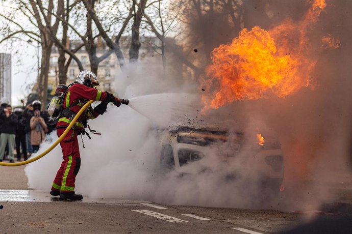 Un bombero apaga el incendio de un coche durante las protesta contra la reforma de las pensiones en París