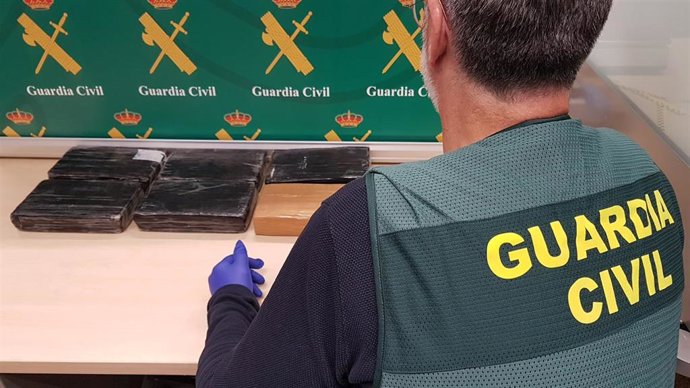 Una agente de la Guardia Civil, frente a los seis paquetes de cocaína incautados.