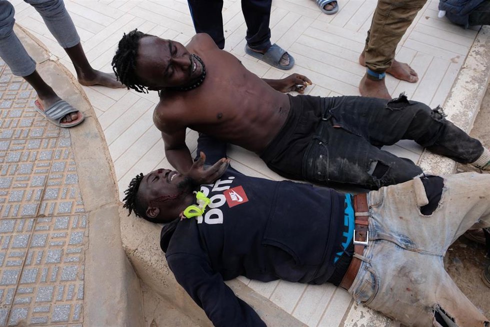Archivo - Dos migrantes descansan tras saltar la valla de Melilla, a 24 de junio de 2022