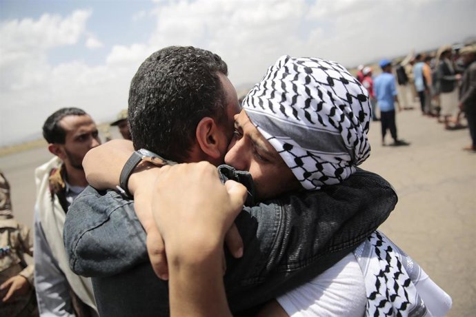 Un prisionero huthi se abraza a un familiar en el aeropuerto de Saná