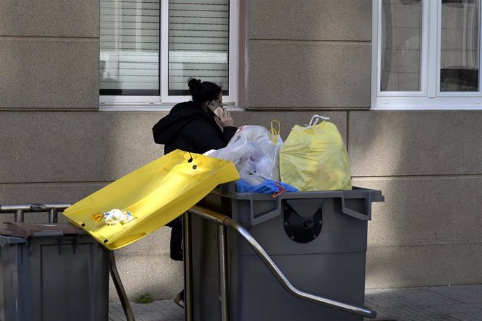 Archivo - Una mujer pasa por un contenedor de basura que rebosa 