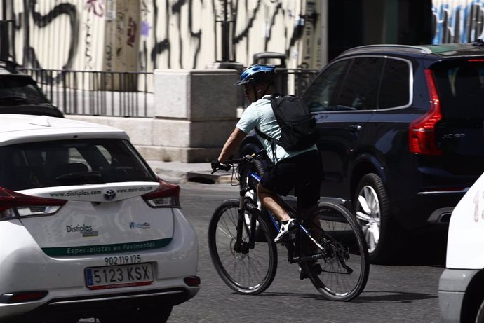Archivo - Un ciclista monta en bicicleta entre coches en la Plaza de España en Madrid.