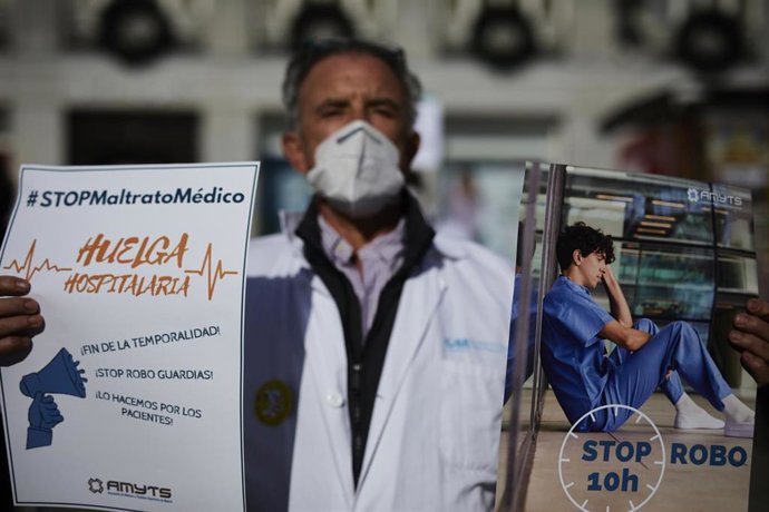 Archivo - Un trabajador sanitario sostiene un cartel durante una concentración convocada por la Asociación de Médicos y Titulados Superiores de Madrid 