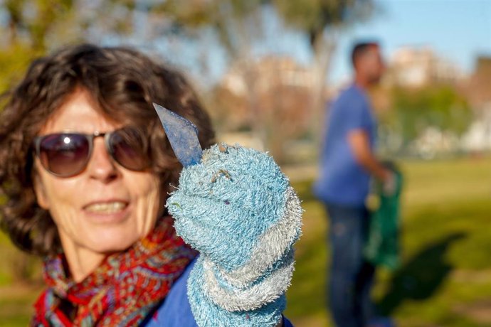 Archivo - Una señora enseña un trozo de vidrio recogido en el Parque del Guadaíra en el día en que miembros de asociaciones vecinales  han organizado una recogida de basura y vidrio.