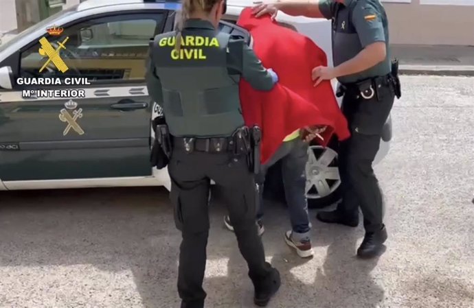 Agesntes de la Guardia Civil introducen en el coche a uno de los detenidos en el punto de venta de drogas en Rosalejo.