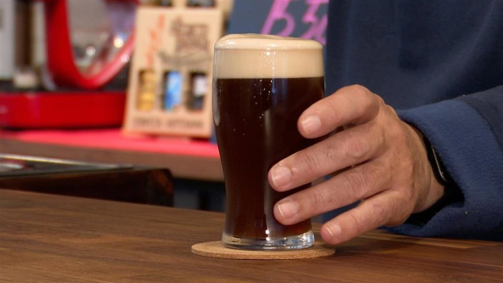 Archivo - Una persona sostiene un vaso de cerveza.