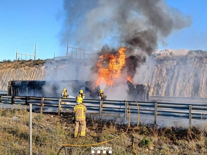 Efectivos de Bombers de la Generalitat trabajan en la extinción del fuego que quema un camión en la vía C-32 a su paso por Vilanova i la Geltrú (Barcelona)