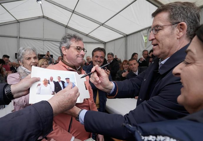 El líder del Partido Popular, Alberto Núñez Feijóo, firma una fotografía durante el acto en Vega de Pas