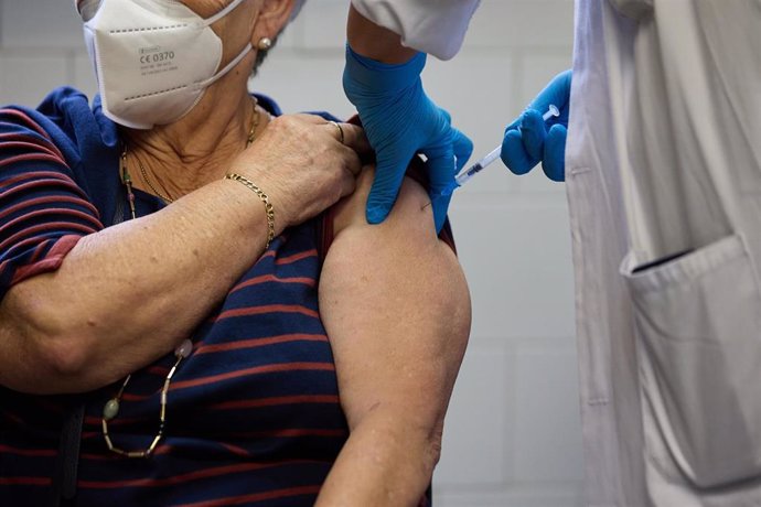 Archivo - Un enfermero vacuna a una mujer en un centro de salud.