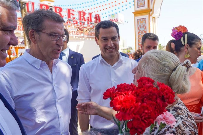 El presidente del PP, Alberto Núñez Feijóo (i), y el presidente del PP-A, Juanma Moreno (d),  con una vendedora de claveles en recinto ferial de Mairena del Alcor para  participan en la presentación de la candidatura del PP la Alcaldía a 20 de abril del