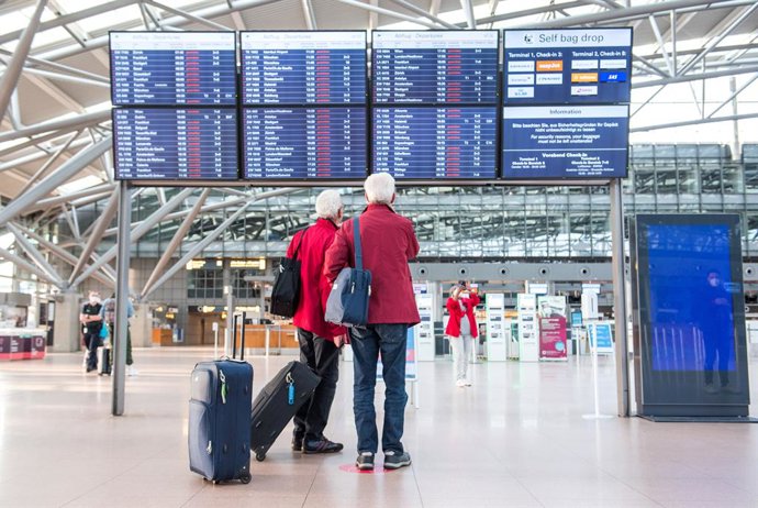 Archivo - 22 March 2022, Hamburg: Two men stand in front of a display panel for flights in a terminal of Hamburg Airport in the early morning. Due to a strike by the ver.di trade union, the security control remains closed for the whole day, no departure