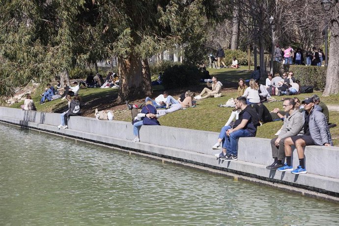 Archivo - Varias personas se sientan cerca del estanque aprovechando el calor en el Parque del Retiro 