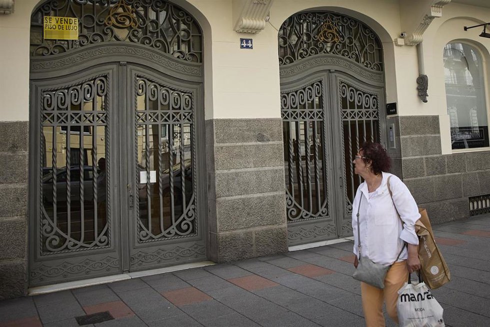 Archivo - Una observa el anuncio de una vivienda de lujo en venta en el barrio de Almagro