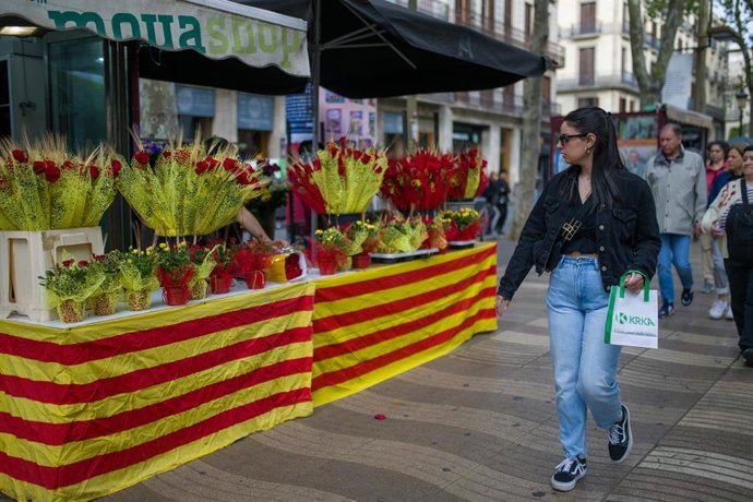 Una chica pasa por delante de un puesto de flores durante la celebración del Día Internacional del Libro , a 23 de abril de 2023, en Barcelona, Cataluña, (España). Barcelona acoge como cada año en la festividad de Sant Jordi a centenares de escritores q