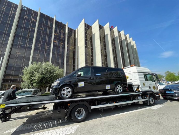 Grúa con un vehículo de VTC encima ante la sede del AMB