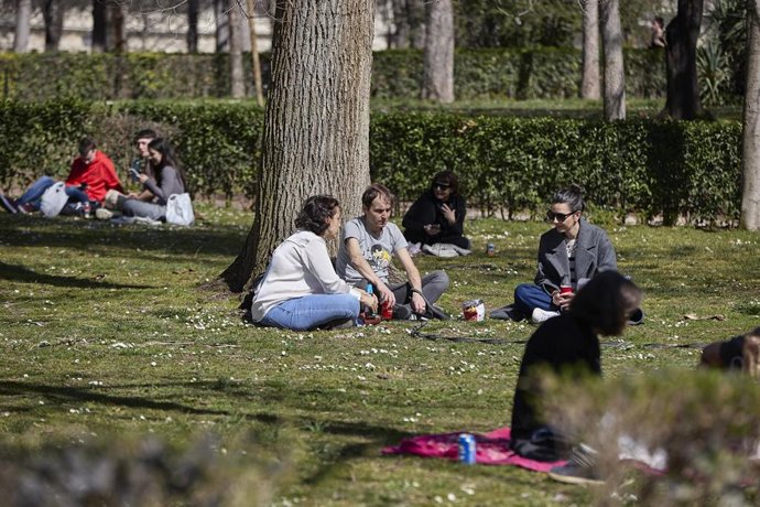 Archivo - Varias personas sentadas en el Parque del Retiro