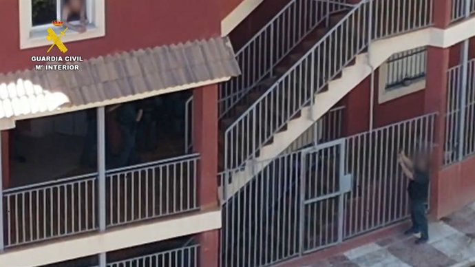 Un agente de la Guardia Civil apunta al hombre que efectuó varios disparos por su ventana en Aguadulce, en Roquetas de Mar (Almería).