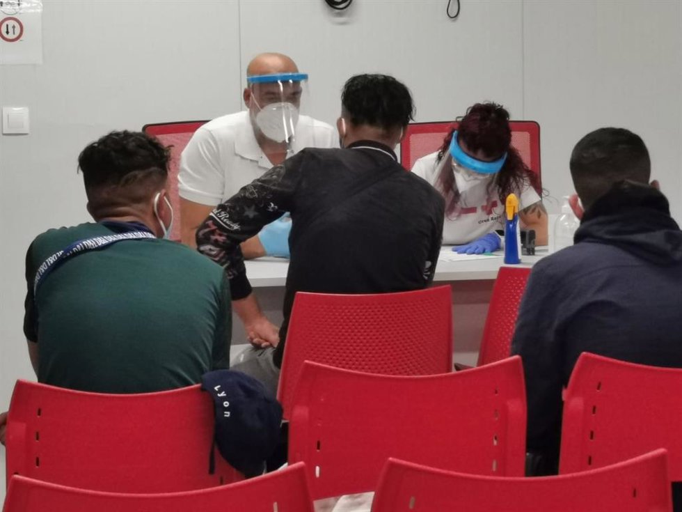 Archivo - Un equipo de Cruz Roja atiende a migrantes llegados al Puerto de Almería.