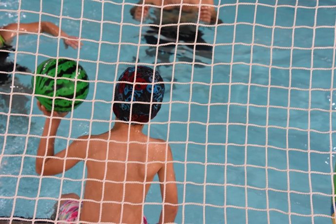 Archivo - Niño con  una pelota en una piscina municipal