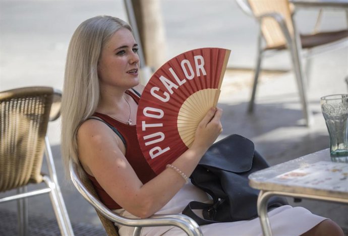 Archivo - Una mujer se abanica en la terraza de un bar.