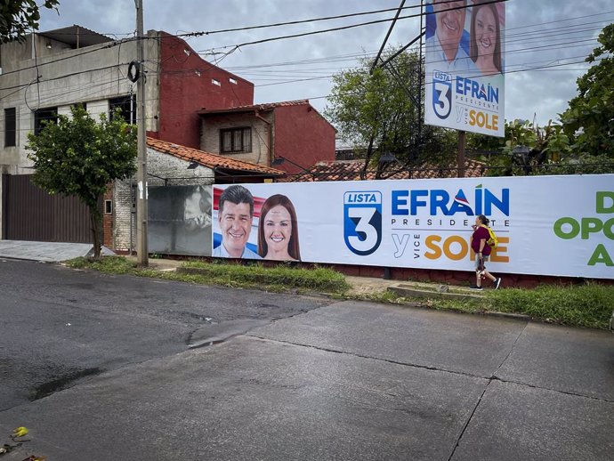 April 13, 2023, Asuncion, Paraguay: A woman walks past a campaign election banner for Paraguay's presidential candidate for the opposition Concertacion coalition, Efrain Alegre (L), and his running mate Soledad Nunez, in Asuncion, Paraguay. Paraguay will 