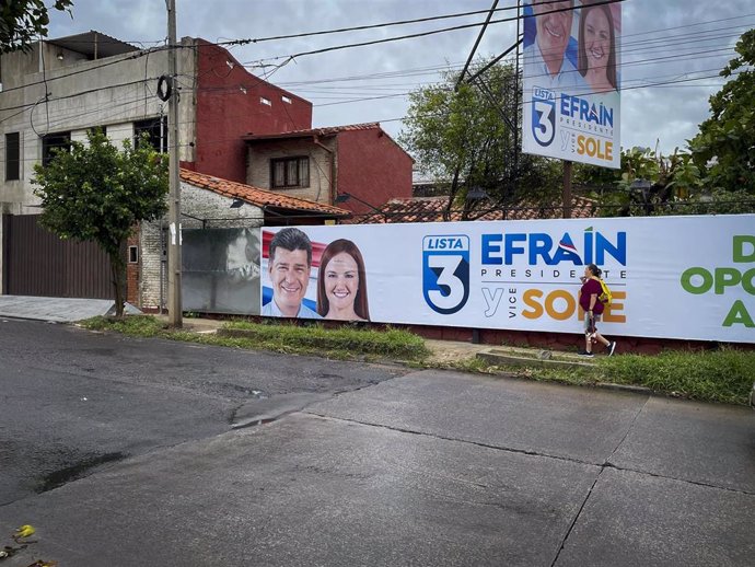 April 13, 2023, Asuncion, Paraguay: A woman walks past a campaign election banner for Paraguay's presidential candidate for the opposition Concertacion coalition, Efrain Alegre (L), and his running mate Soledad Nunez, in Asuncion, Paraguay. Paraguay wil