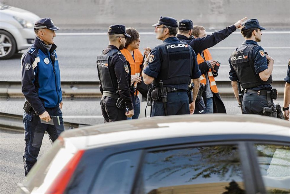 Dos activistas de Futuro Vegetal junto a varios agentes de Policía Nacional tras participar en la acción de colgar dos pancartas en una señal luminosa de la M-30, a la altura de Puente de Vallecas, a 10 de abril de 2023, en Madrid (España). Las dos acti