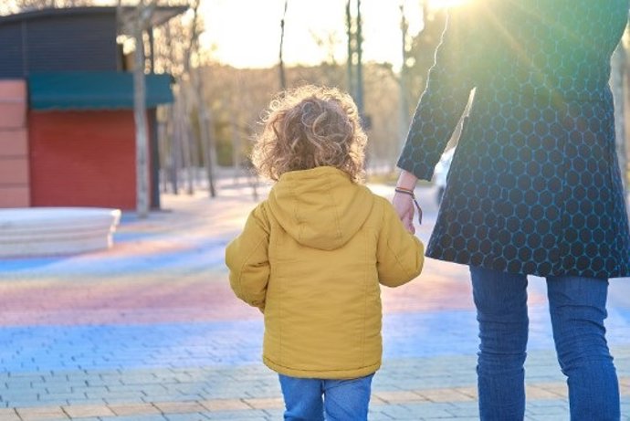 Una madre pasea con su hijo de la mano