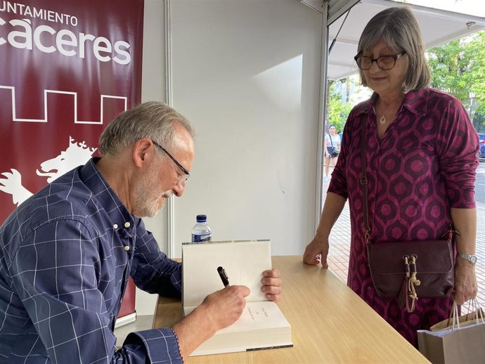 El escritor Jorge Molist firma un ejemplar de su obra en la Feria del Libro de Cáceres.